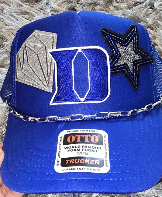 Duke Blue Devils emblem and a silver diamond patch, hat chain and a blue and silver star